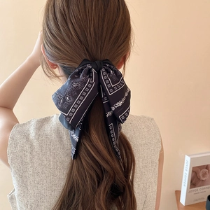Macro shot of black paisley bow hair tie styled on a ponytail for elegant look