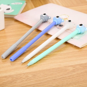 Set of four cute cartoon koala gel pens with silicone toppers on a wooden desk background