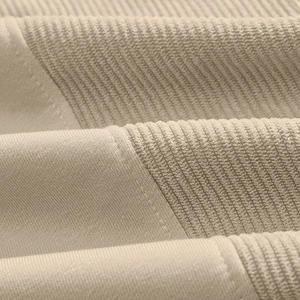 Macro detail of beige corduroy fabric texture and ribbed knit stitching on the sweatshirt