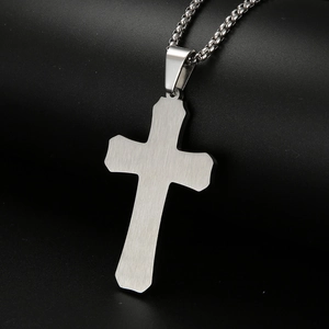 Gros plan d'un collier pendentif croix en acier inoxydable argenté sur fond noir