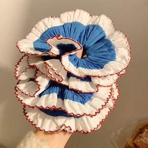 Detailed shot of large blue and white pleated lace scrunchie with red stitching