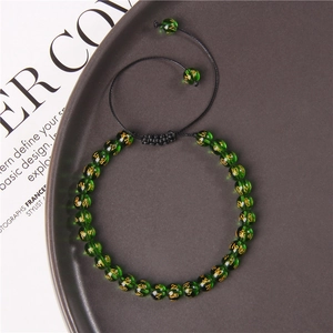 Detail of green 6mm stone beads with gold patterns on adjustable black braided cord