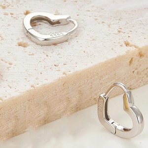 Detailed view of 925 sterling silver heart studs showing the S925 hallmark on polished metal
