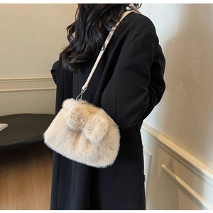 Detail of soft beige faux fur bucket bag with silver hardware on a black coat