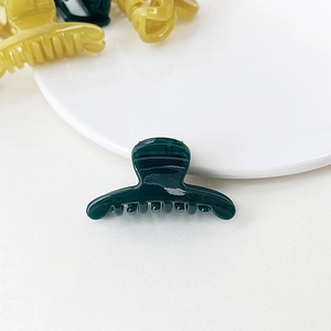 Detail of small jelly texture hair clips in dark green, amber yellow and black acrylic
