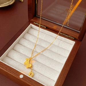 Detailed view of a gold zodiac rabbit and coin pendant in a premium wooden jewelry box