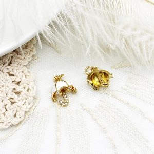 Detailed close-up of golden umbrella pendant with white enamel and zircon accents