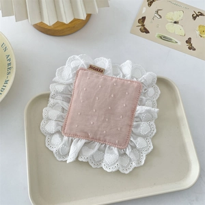 Detailed view of pink cotton coaster with white lace borders and brand label decor
