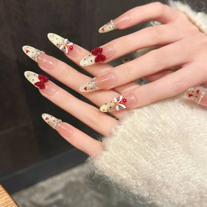 Handmade lion dance press-on nails with red bows and gold glitter in long stiletto shape