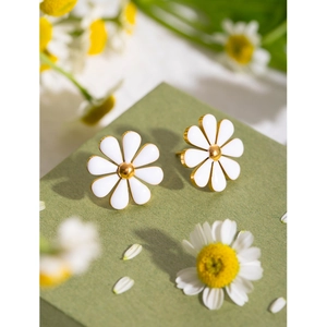 Macro shot of 18k gold plated stainless steel daisy earrings on a green gift box
