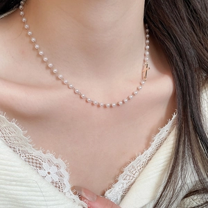 Close-up of elegant pearl choker necklace with a minimalist gold cross pendant for women