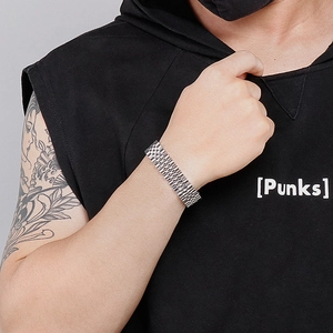 Close-up of a men's silver steel watch-style bracelet worn on wrist over dark clothing