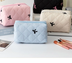Dettaglio di trousse trapuntate con ricamo a fiocco disponibili in vari colori pastello