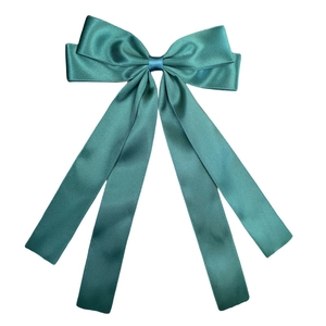 Detailed view of teal silk bow hair clip showing elegant ribbons and glossy texture