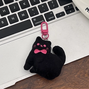 Close-up of a cute black plush cat keychain with pink bow and metallic pink hook