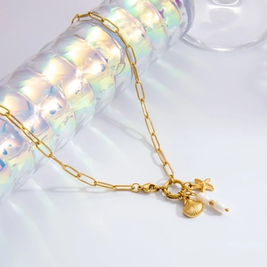 Detailed close-up of golden shell, starfish pendants and pearls on a sleek chain necklace