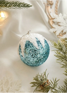 Détail de boule de Noël à paillettes bleu ciel avec effet neige et décor de branches
