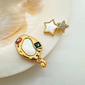 Macro detail of star-shaped stud and geometric shell pendant with inlaid gemstones