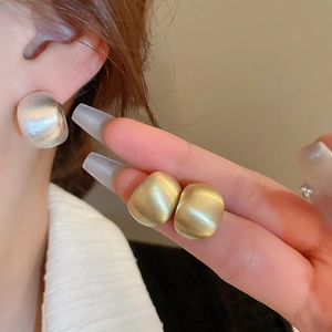 Detail of gold and silver C-shaped brushed metal earrings with matte cat-eye gloss texture