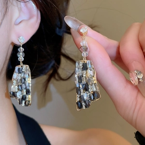 Macro shot of geometric crystal drop earrings with sparkling rhinestones in gold setting