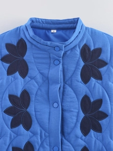Detail of blue quilted jacket with black embroidery and S size label in neck