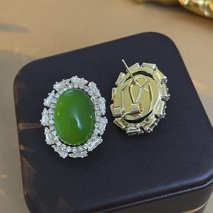 Macro detail of vintage gold plated oval green stone earrings with zircon stones