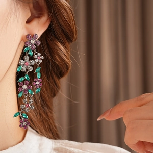 Gros plan de boucles d'oreilles fleurs vintage avec cristaux roses et verts sur modèle