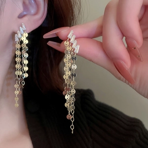 Close-up of golden leaf tassel earrings with sparkling rhinestones worn by a model