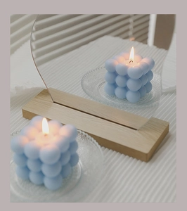 Close-up of blue bubble cube candle with wood base and decorative acrylic mirror