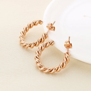 Élégante paire de boucles d'oreilles créoles torsadées en acier inoxydable or rose sur plateau