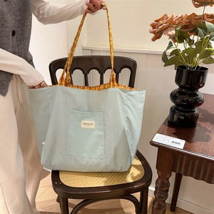 Detail of mint green canvas tote bag with yellow checkered strap on vintage chair