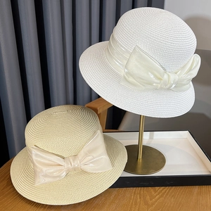 Detailed close-up of woven straw sun hats featuring elegant satin bow decorations