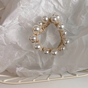 Close-up of elegant beige woven elastic hair tie with large white pearls in a basket