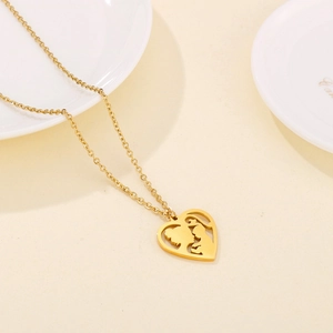 Detailed view of golden heart pendant with mother and child silhouette on white porcelain