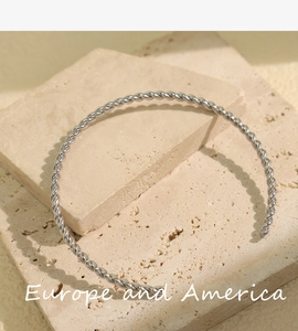 Macro detail of silver twisted cable cuff bracelet on a natural textured stone background