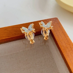 Detail of 18k gold butterfly ear clip with blue resin wings and white zircons