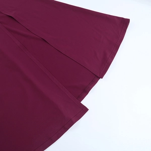 Détail de l'ourlet de robe bordeaux montrant les coutures et la texture du tissu
