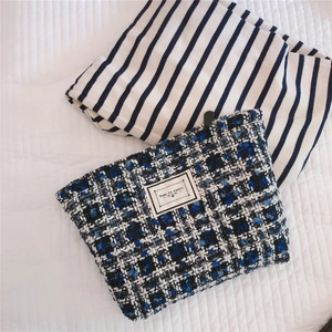 Detail of blue and black tweed cosmetic bag with TIME TO PARTY square patch text
