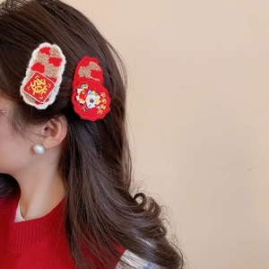 Detail of red and cream New Year hair clips with embroidery and festive symbols