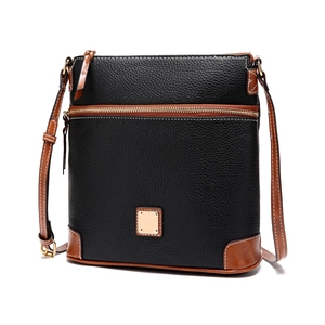Detail of lychee textured black leather crossbody bag with brown trim and golden hardware
