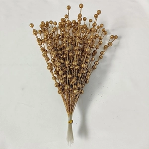 Close-up of golden artificial berry stems with glitter finish for holiday decor