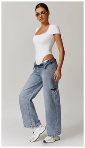Dettaglio del body bianco a costine con bordo in pizzo e abbinamento denim blu