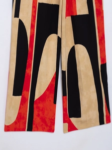 Close-up of geometric abstract print on lightweight beige black and red trousers
