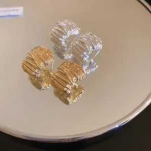 Artistic gold and silver textured earrings with metallic fold design on mirror