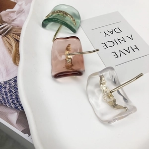 Three pairs of resin geometric earrings in green, brown and clear with golden accents