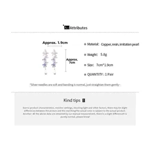 Detail view of flower drop earrings with resin petals and white teardrop pearl accents
