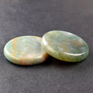 Detailed view of polished 40mm green and brown jade crystal discs with natural texture