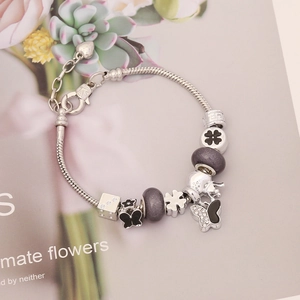 Macro detail of DIY charm bracelet featuring purple frosted beads and crystal butterfly