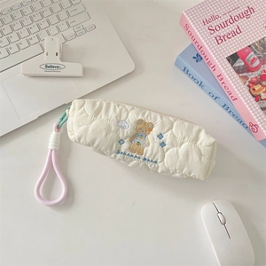 Detail of quilted pencil case with sunbeam bear embroidery in a desk setup