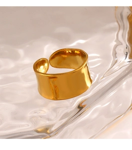 Macro shot of gold wide band ring with hammered texture on a glass tray